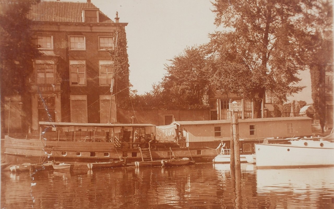 Huis Van Gijn op een vergeelde foto. De haven met een boot, het huis, de bomen hebben blad.