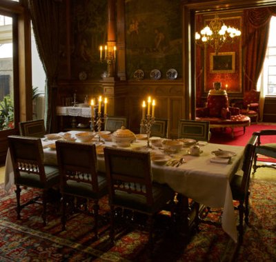 Sfeervol gedekte eettafel in kerstsfeer. Er staan brandende kaarsen op tafel.