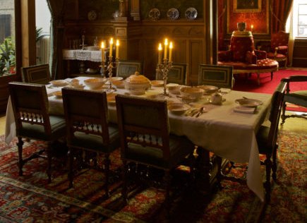 Sfeervol gedekte eettafel in kerstsfeer. Er staan brandende kaarsen op tafel.