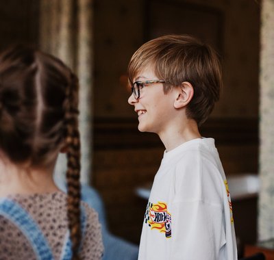 Twee kinderen in Huis Van Gijn. Het jongetje lacht, het meisje staat wazig op de voorgrond.