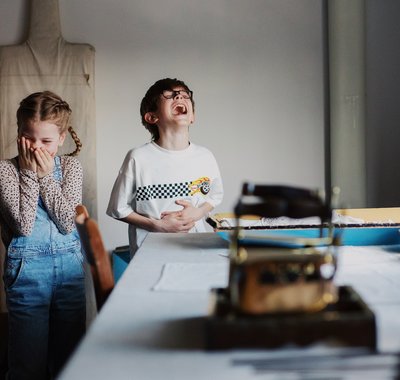 Twee kinderen, een jongen en een meisje, staan in de wasruimte. Ze lachen heel hard.