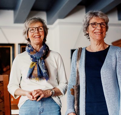 Twee dames bekijken een kamer in Huis Van Gijn. Ze lachen.