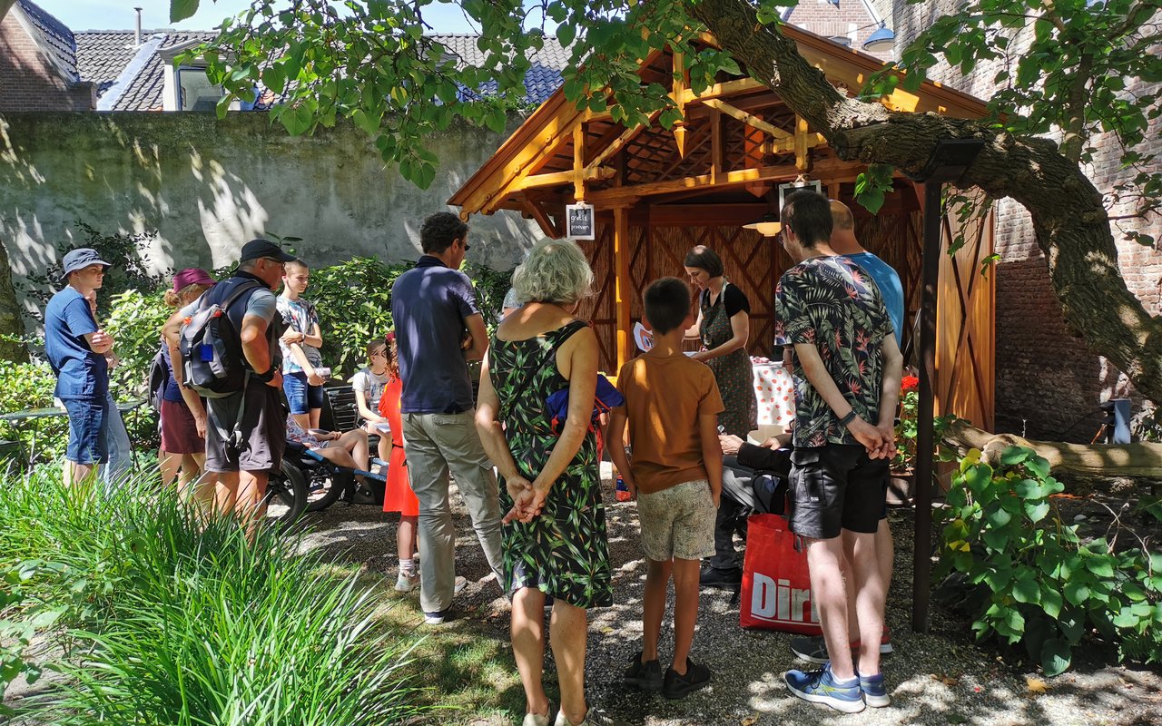 Ijs-middag in Huis van Gijn. Er staat een menigte met ouders en kinderen in de tuin Huis Van Gijn. In het tuinhuisje wordt ijs handgemaakt.