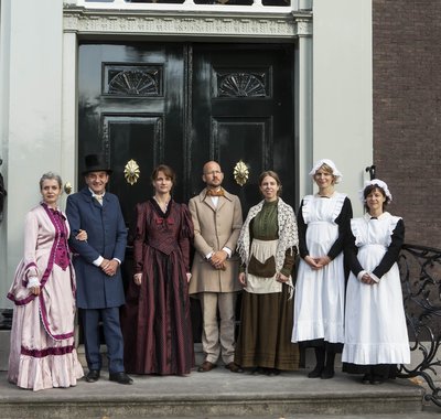 Het personeel staat samen met de heer en vrouw des huizes voor het huis op het bordes.