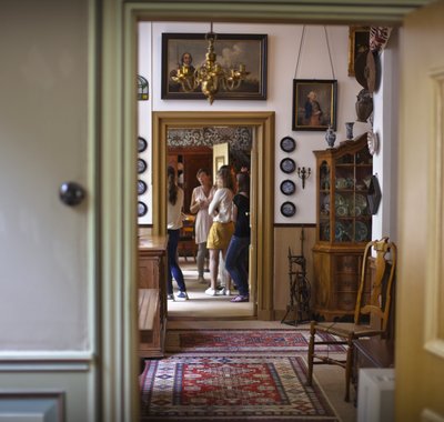 Jongeren staan stil in een kamer in Huis Van Gijn, terwijl zij uitleg krijgen door de rondleidtser.