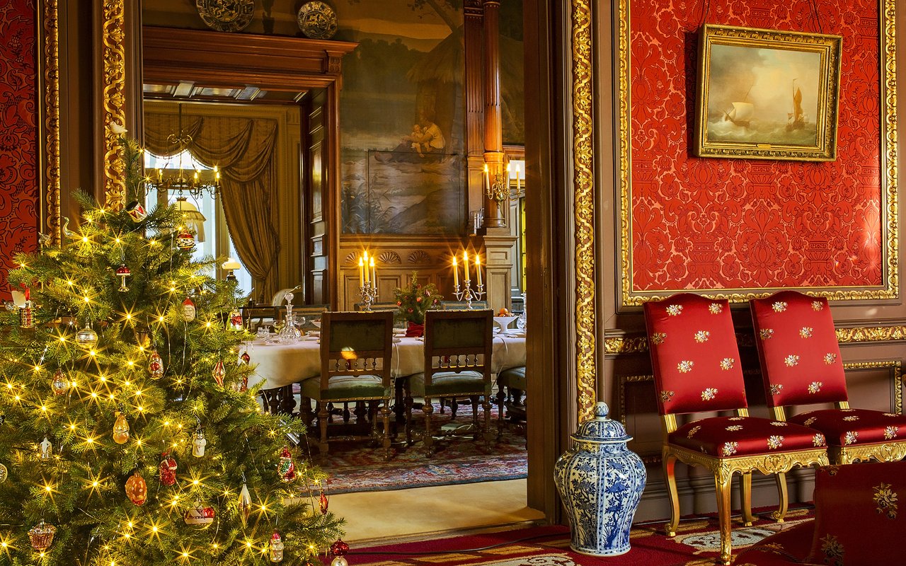 Een doorkijk vanuit de Vriesendorpsalon naar de eetkamer. Een versierde kerstboom staat links en in het midden zie je de feestelijk gedekte eettafel.