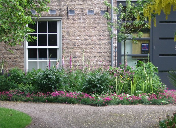 Border met bloemen in wit en roze tinten. Een grindpad loopt voorlangs.